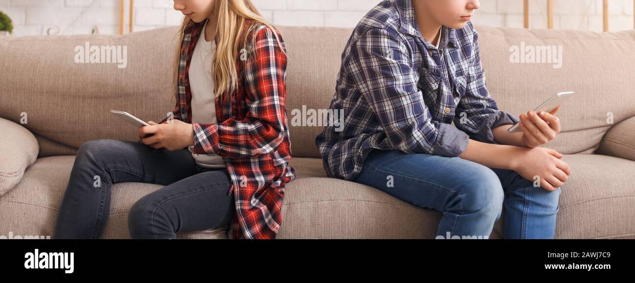 Boy And Girl Using Smartphones Sitting On Sofa, Cropped, Panorama Stock Photo