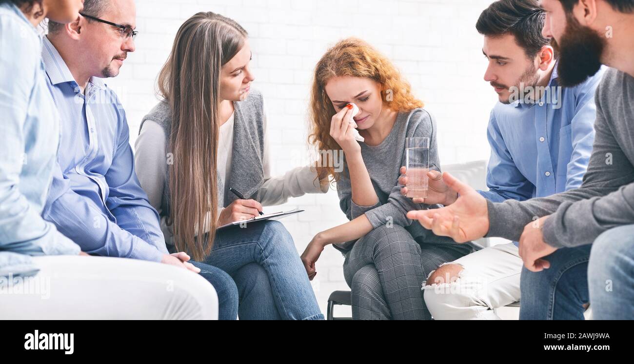 Depressed crying woman receiving empathy from Support Group members Stock Photo
