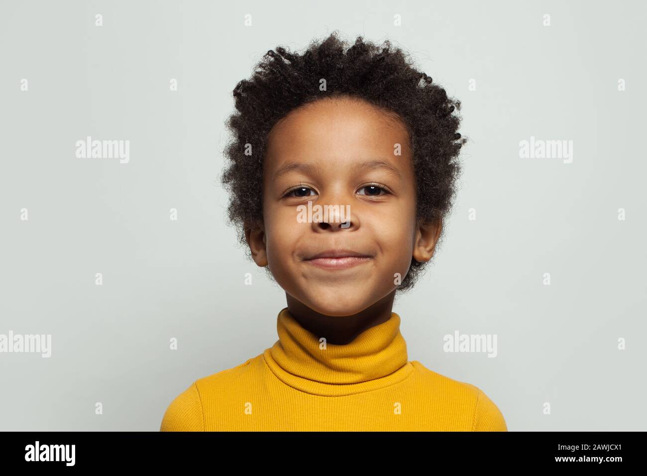 Little black kid boy smiling on white background, close up portrait