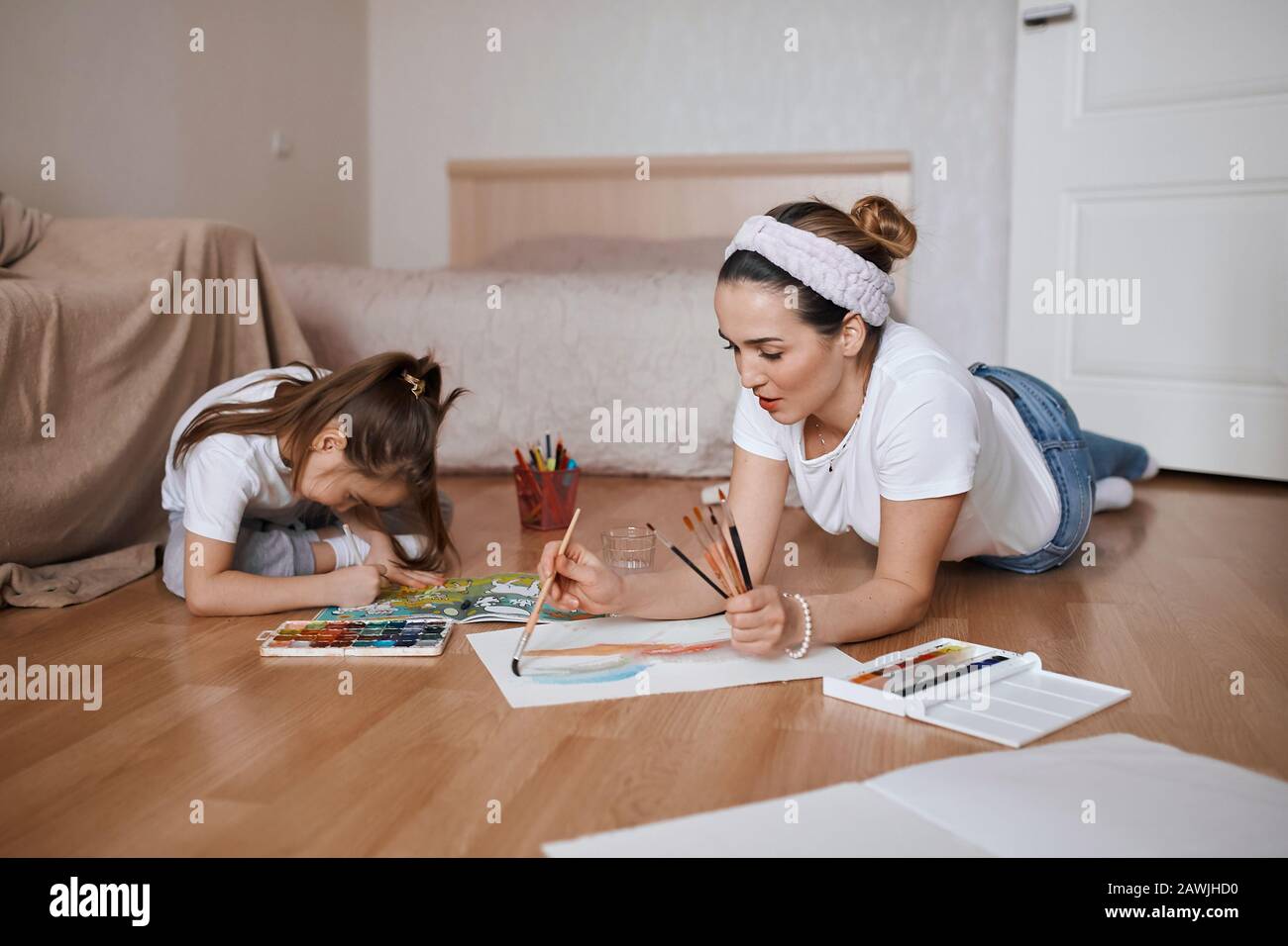 young woman and her daughter enjoying drawing, painting process, close up photo, happiness, useful time, woman and girl attending painting lesson Stock Photo