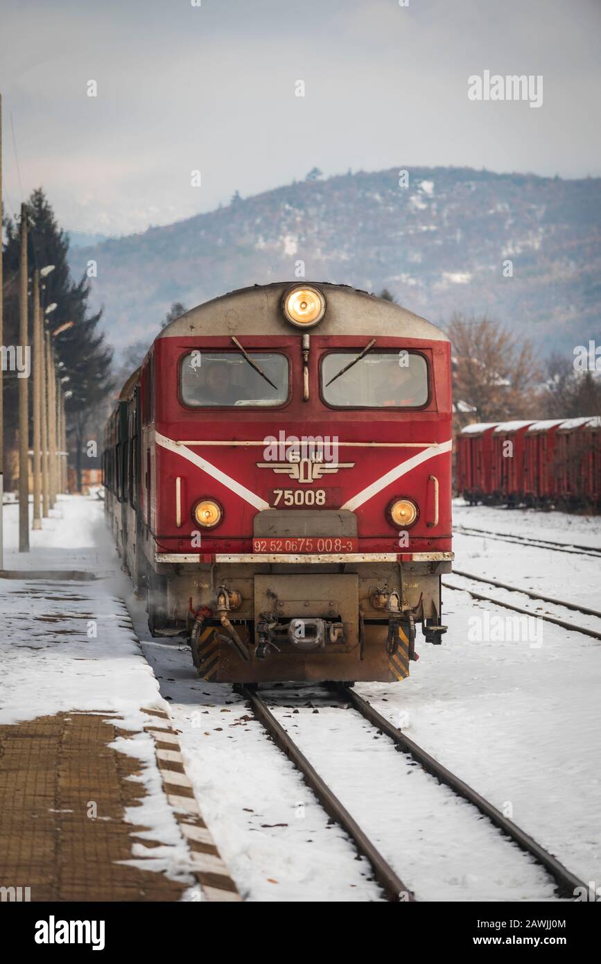 Velingrad railway station, Bulgaria - February 8, 2020: Train with red locomotive and green wagons arrives at the train station. Stock Photo