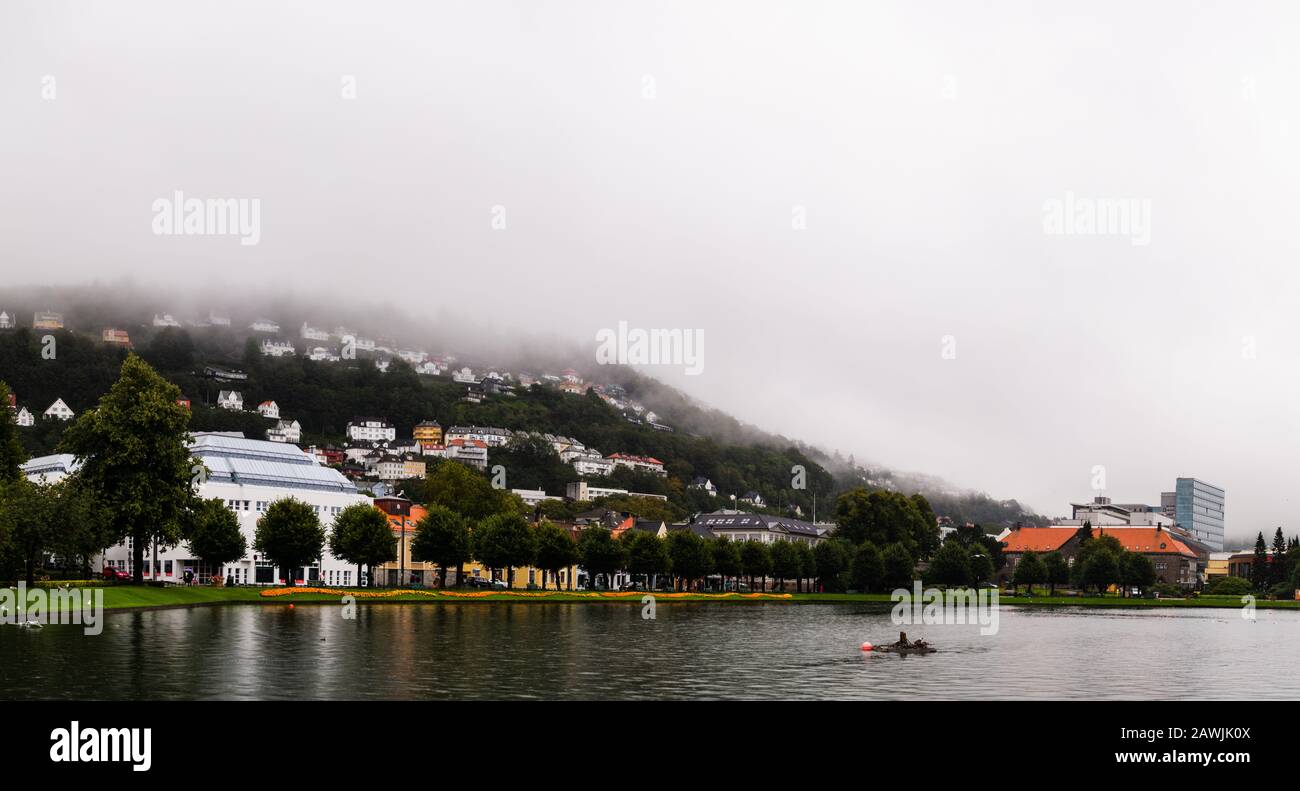 Editorial 09.04.2019 Bergen Norway View of the central park with lake in the city with fog covering the homes on the hillside of Floyfjellet mountain Stock Photo