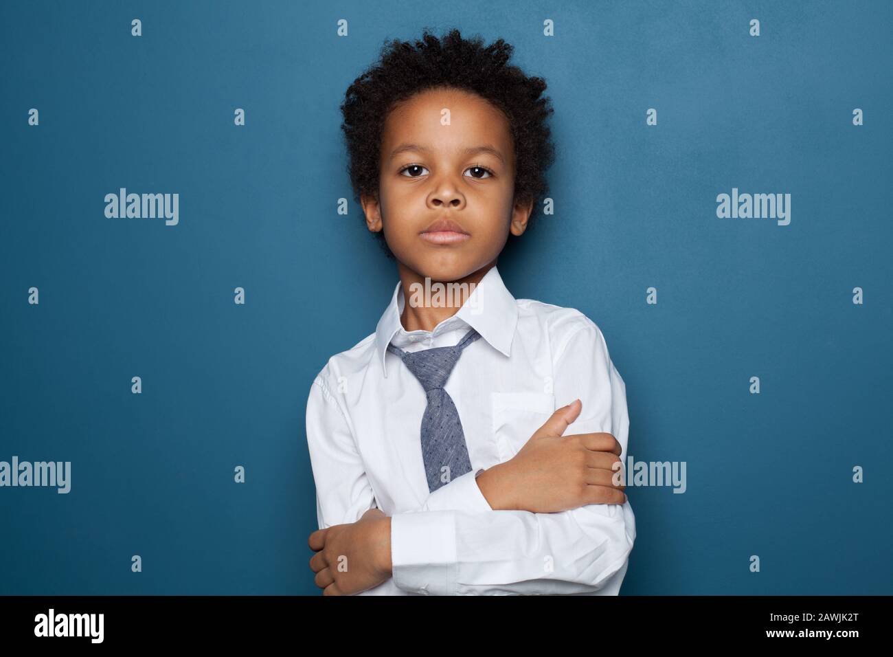 Smart black kid boy student with crossed arms on blue background. Little child  school boy Stock Photo
