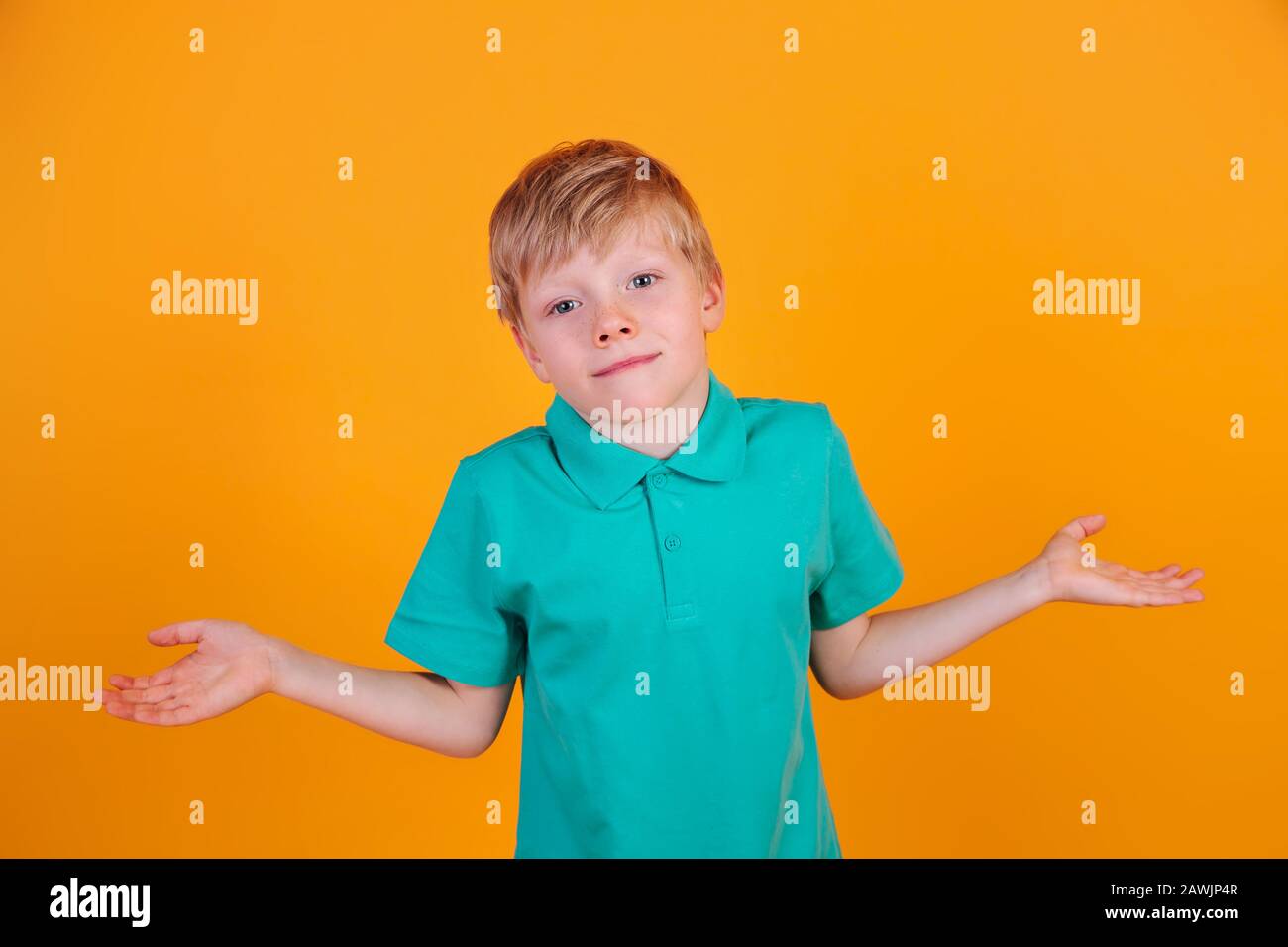 Blond boy in blue t-shirt making indifferent gesture, having confused look, shrugging his shoulders. I don't know Stock Photo
