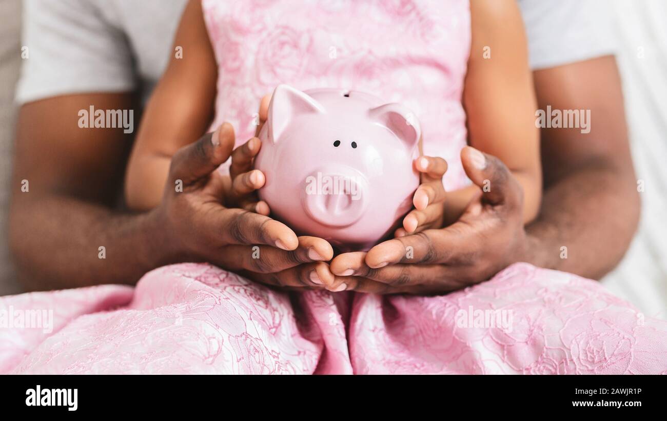 Black father and daughter holding piggy bank, close up Stock Photo - Alamy