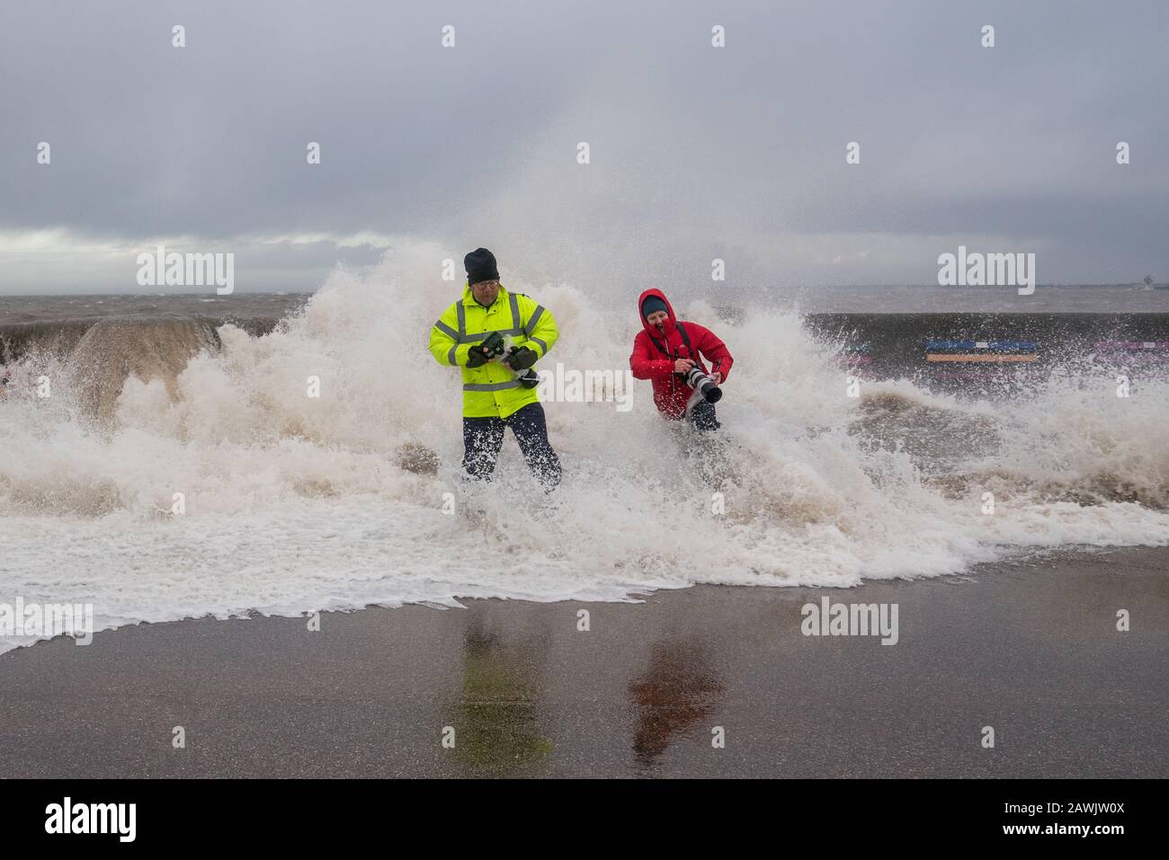 New Brighton, Wirral, UK. 9th Feb, 2020. Photographers take the opportunity to try and capture the waves caused by Storm Ciara, as they crash into the promenade at New Brighton on the Wirral. One photographer is swept off their feet by the waves crashing over the promenade wall. Credit: Christopher Middleton/Alamy Live News Stock Photo