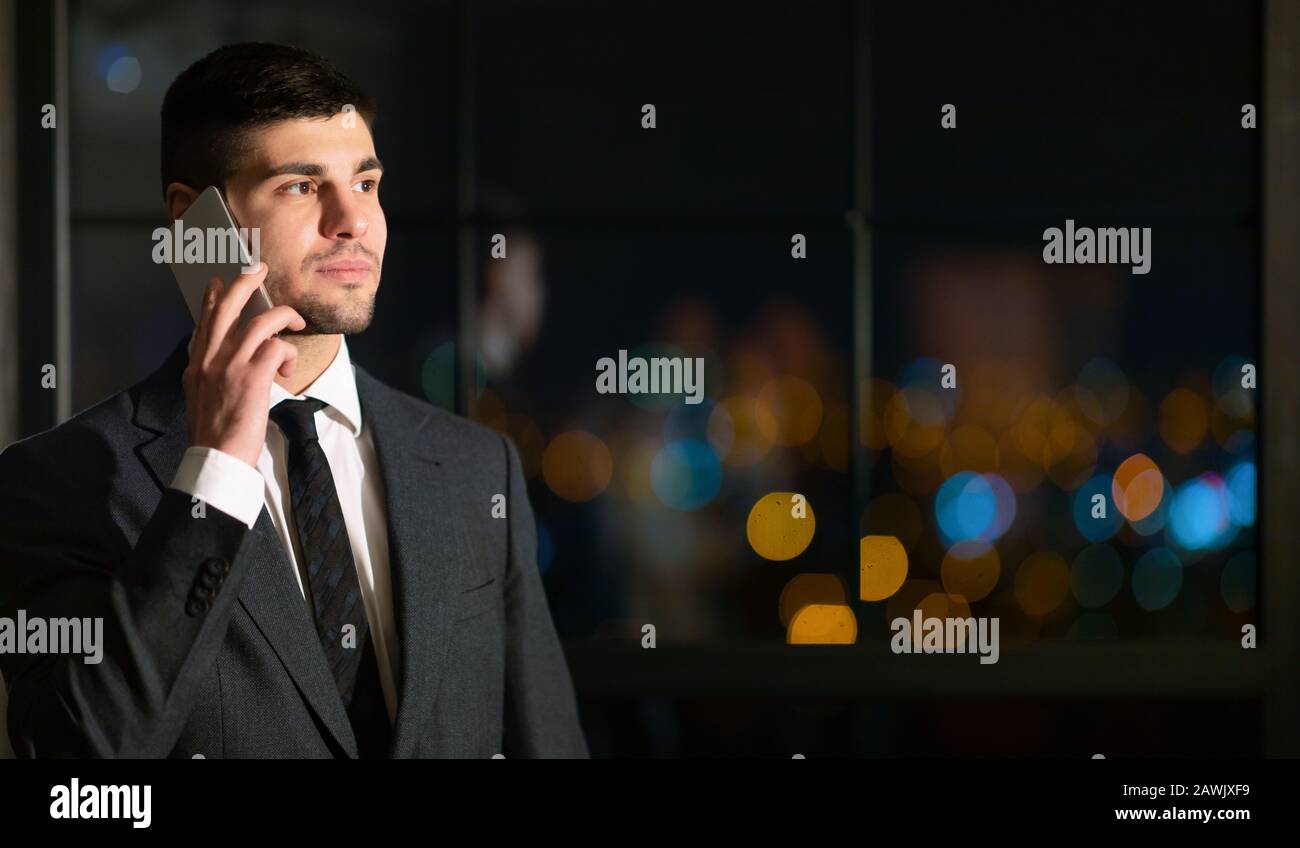 Businessman Talking On Mobile Phone Standing In Night Office Stock Photo