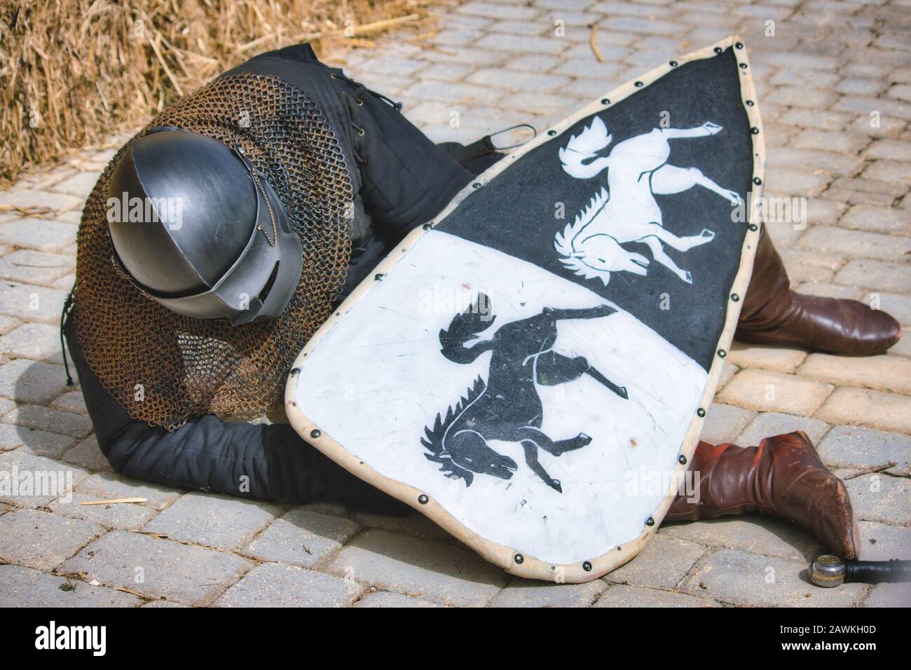 A medieval knight in full body armour lying injured on the ground Stock Photo