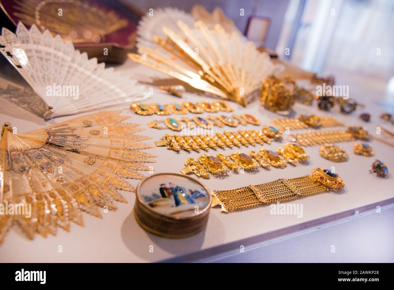 Luxury gold jewelry - shiny gold bracelets and handheld fans. variety of beautiful antique jewelry of royal family on display at shop. Expensive Gift Stock Photo