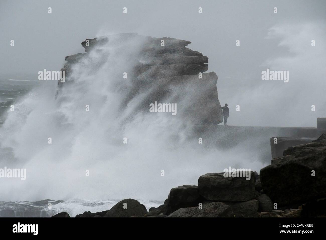 Portland Bill, Dorset, UK.  9th February 2020. UK Weather.  A thrill seeker risks his life by walking onto Pulpit Rock at Portland Bill in Dorset and risks being swept in to the sea as huge waves from Storm Ciara crash against the limestone pillar.  Picture Credit: Graham Hunt/Alamy Live News Stock Photo