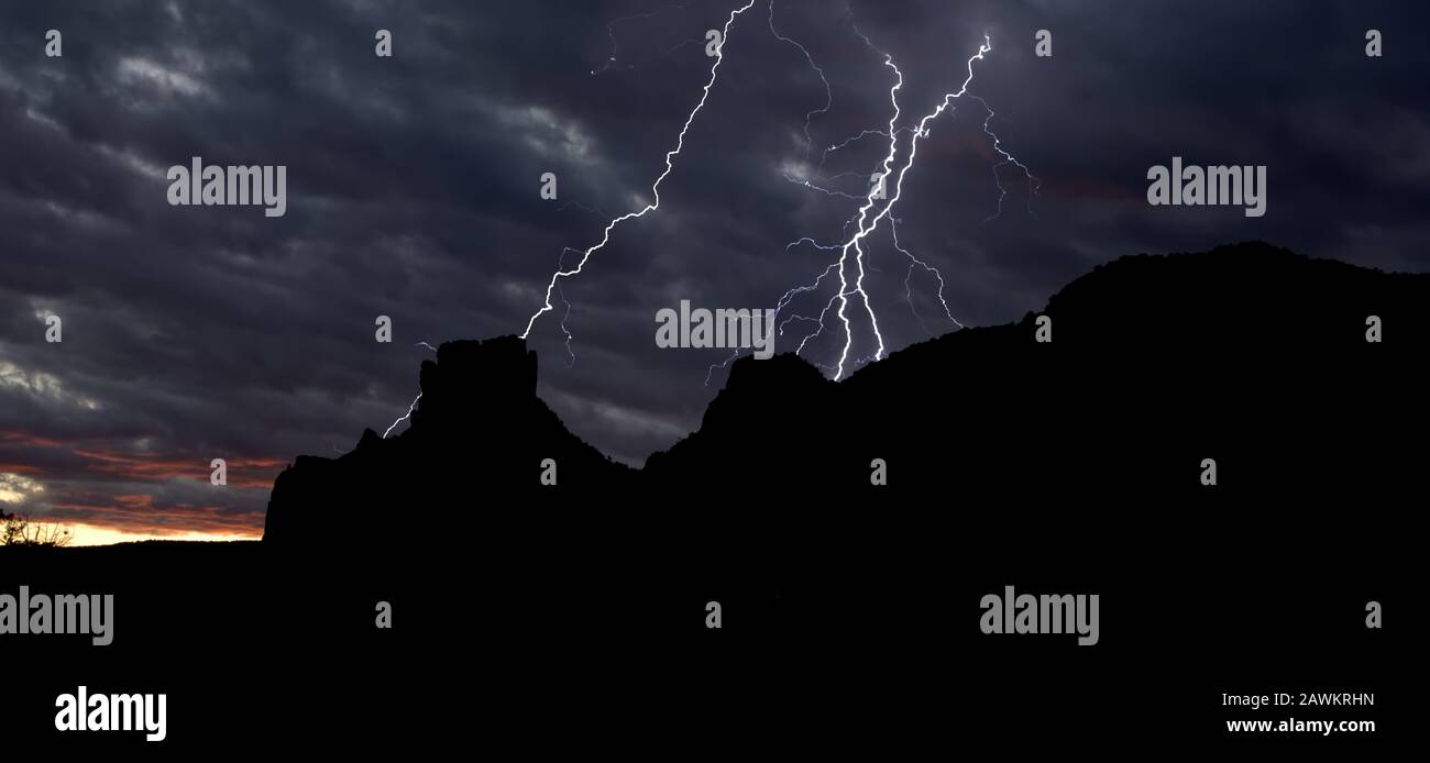 Lightning striking behind Castle Rock in Sedona AZ at sundown. Stock Photo