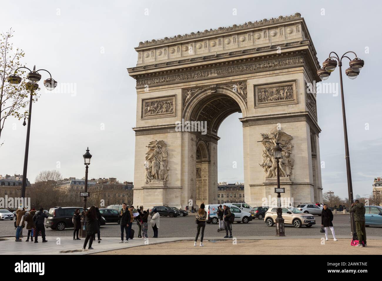 View on the Arc de Triomphe de l'Étoile (Triumphal Arch of the Star). Tourists and typical parisian traffic in the foreground. National monument. Stock Photo