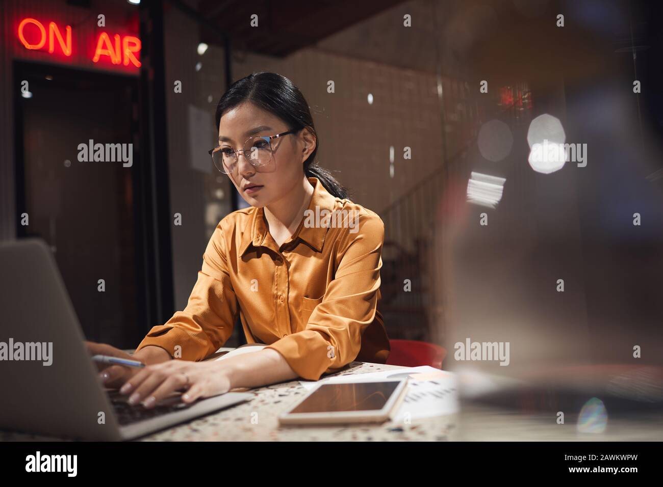 Portrait of Asian businesswoman using laptop while working late in dark office, copy space Stock Photo