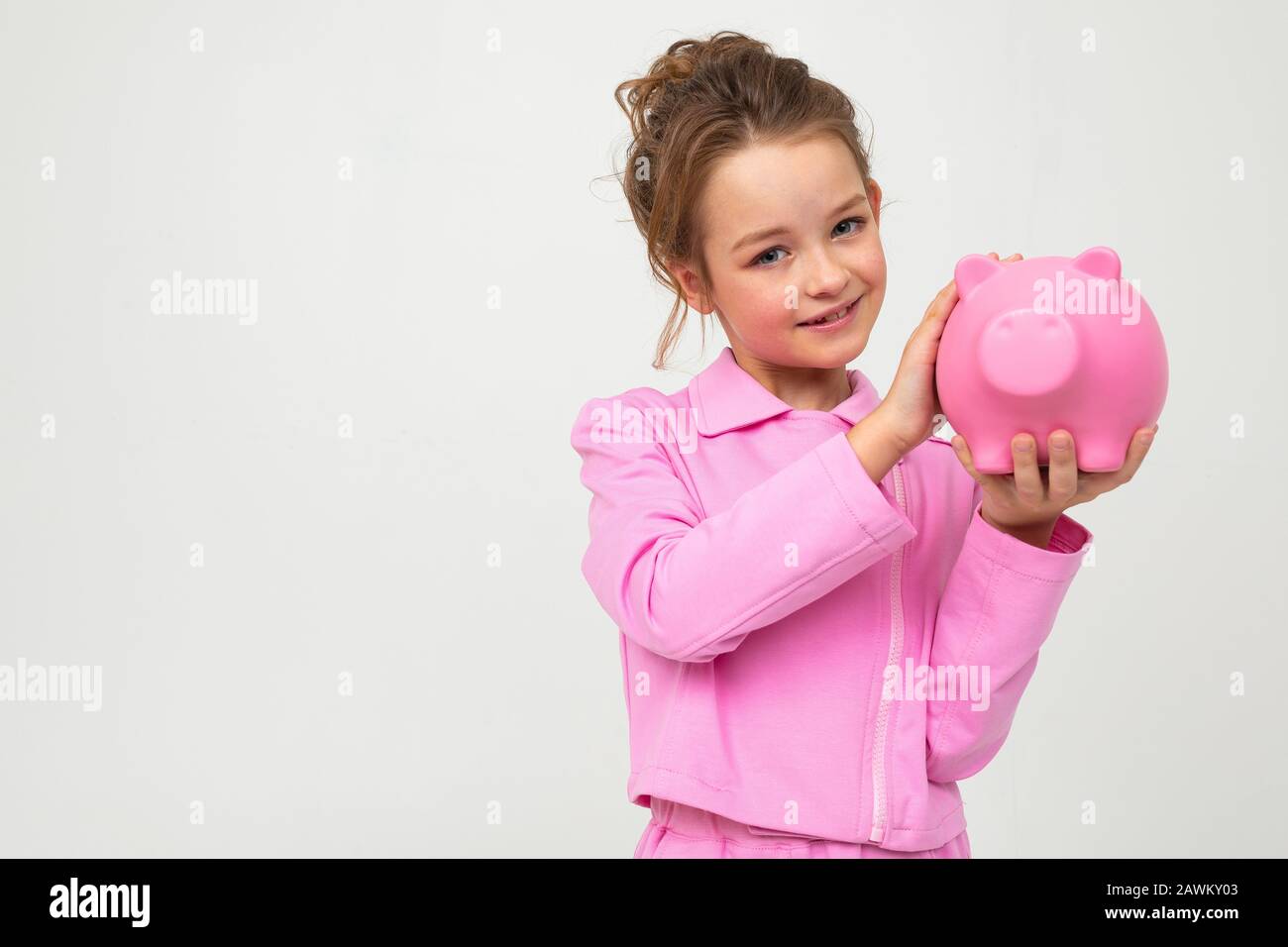 finance. portrait of a girl in a pink suit holding a piggy bank on a ...