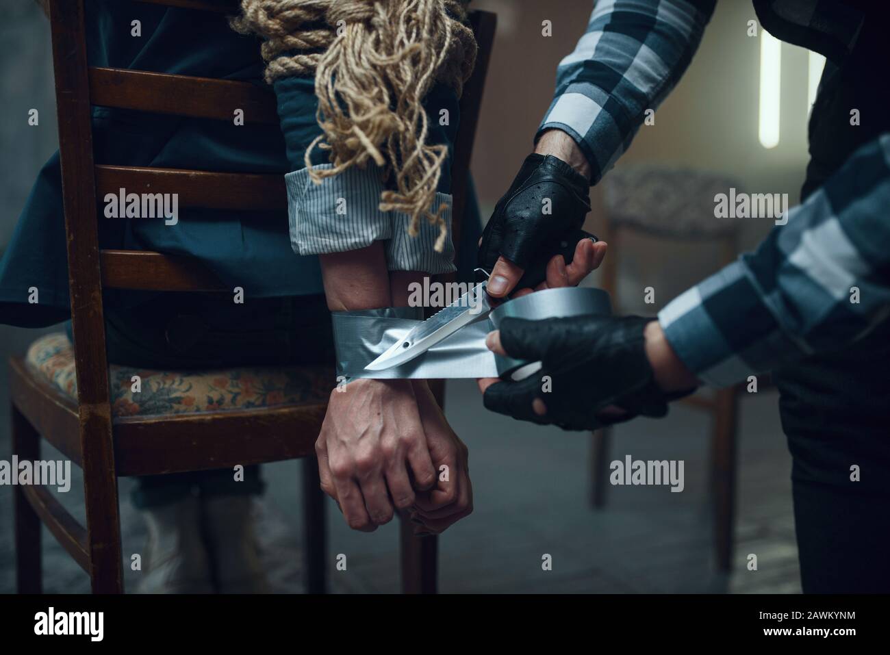 Maniac kidnapper taping his female victim's hands Stock Photo