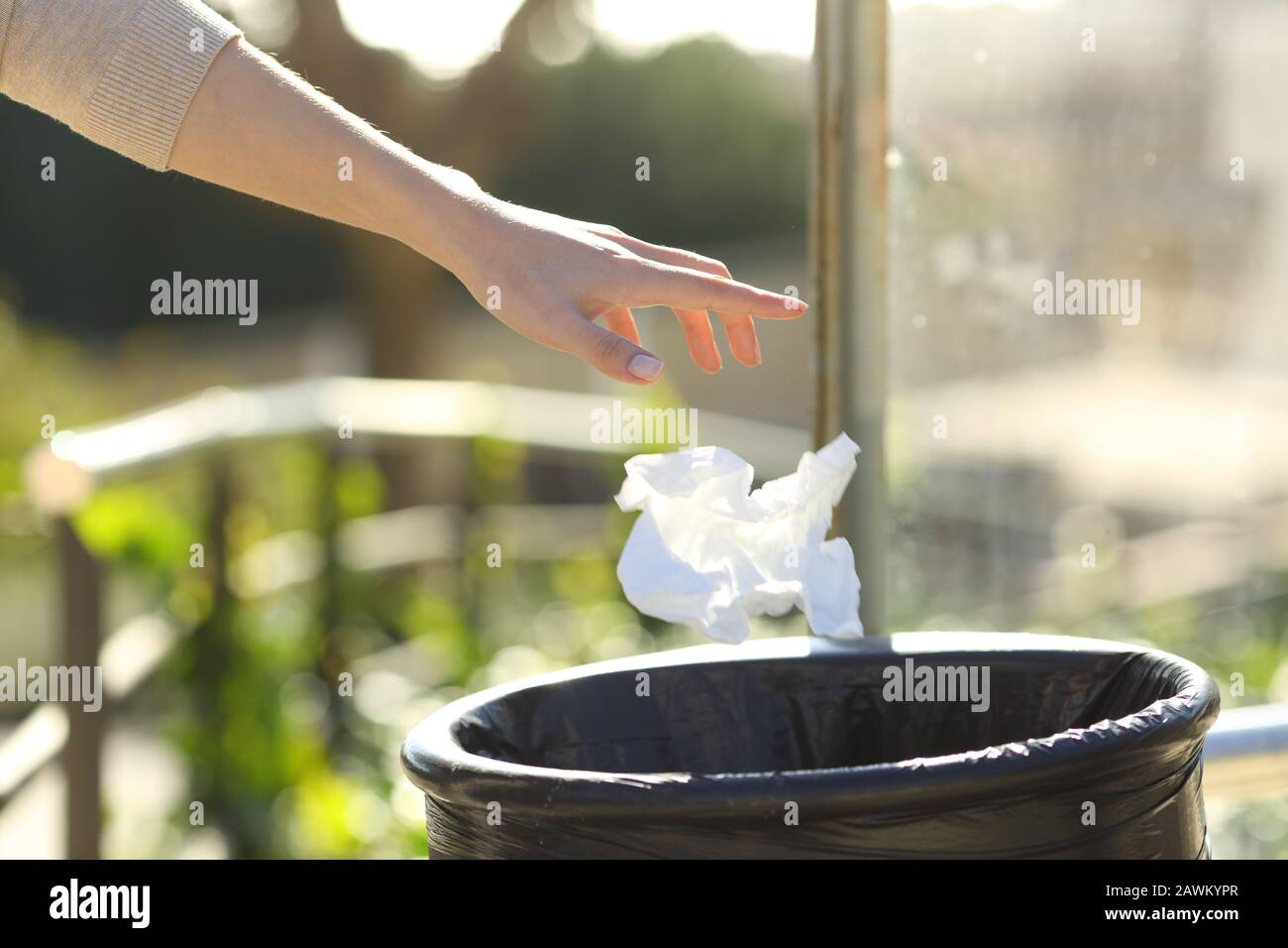 Close up of a woman hand throwing litter into bin in a park Stock Photo