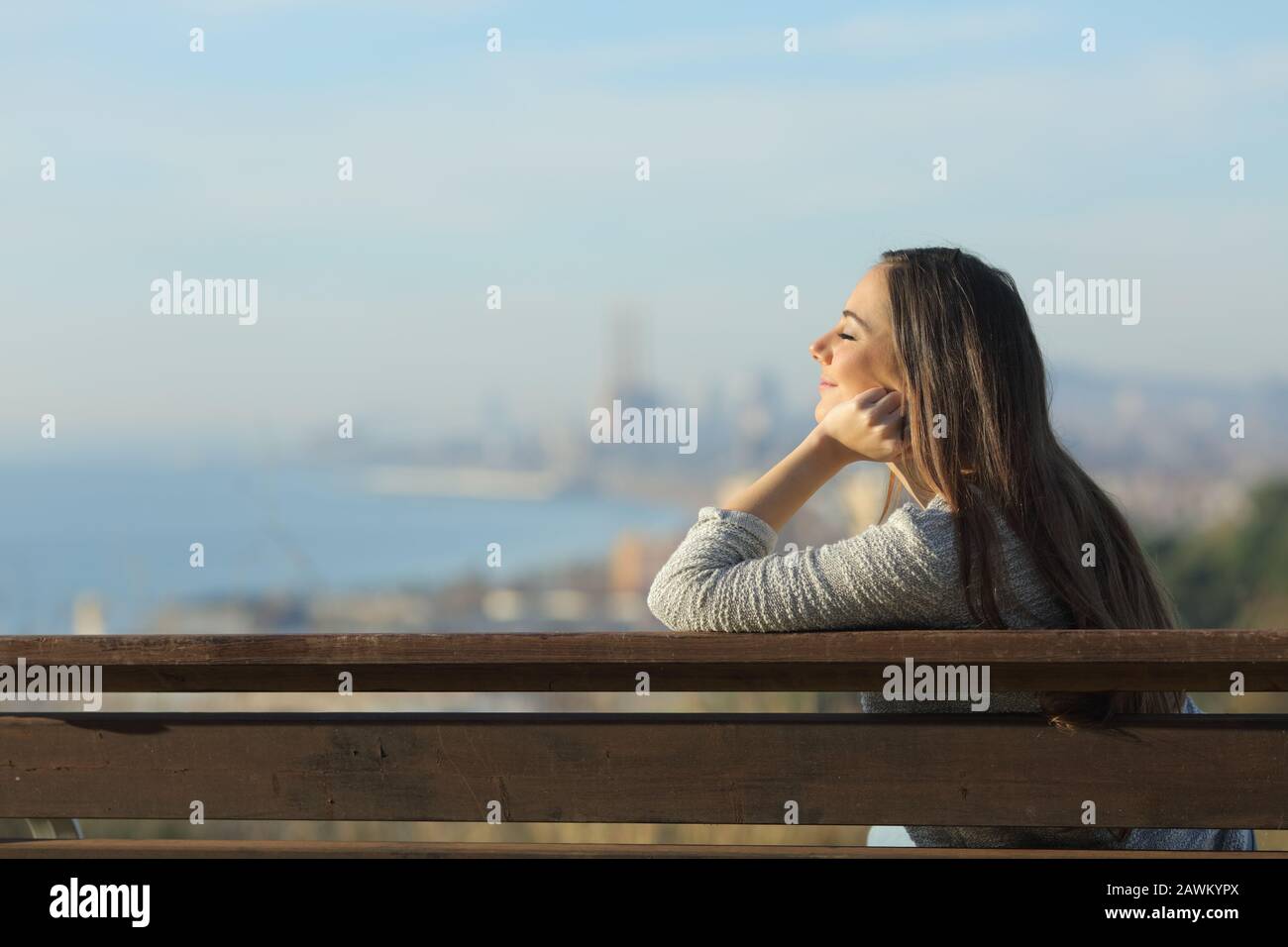 Side view portrait of a relaxed woman sitting in a bench with closed ...