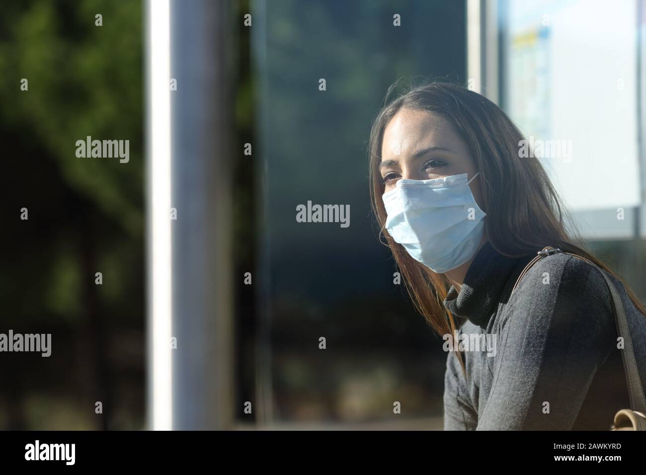 Woman wearing a protective mask to prevent virus contagion waiting in a bus stop Stock Photo