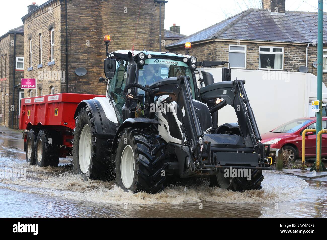 Marsden, UK. 9th February, 2020. Storm Ciara leaves a trail of damage in the Calder valley.  Rain has washed stones and  a railway sleeper onto the Rochdale to Todmorden Road.  A tree has fallen across the railway line.  A tractor is been used to take away flood water and empty it into the Rochdale canal.  Walsden, Calder Valley, West Yorkshire, UK. Credit: Barbara Cook/Alamy Live News Stock Photo