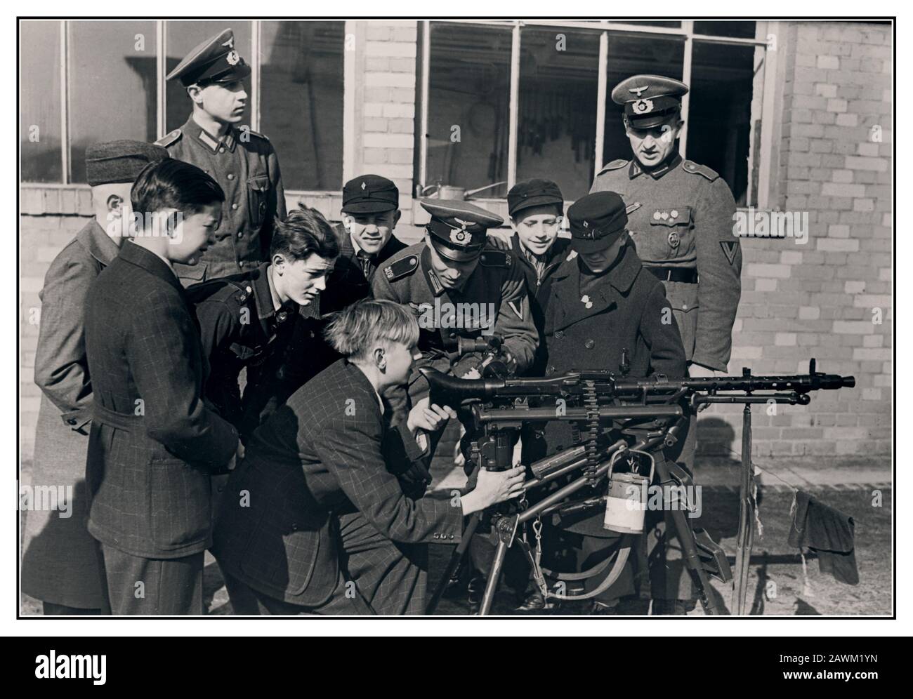 Vintage WW2 1940’s German Nazi Wehrmacht officers teach and train German Hitler Youth boys, the Hitlerjugend, the youth movement of the Nazi Party, how to operate a MG-34 machine gun to enable its members to fight faithfully for Nazi Germany as soldiers.1942. World War II Second World War Stock Photo