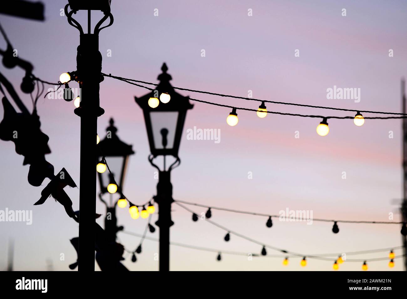 Light bulbs and street lamps at dusk as lights start to come on in St