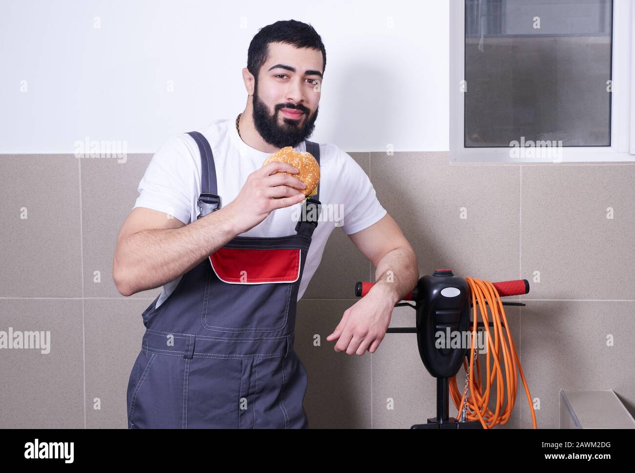 Worker wearing uniform eating burger during a lunch break Stock Photo