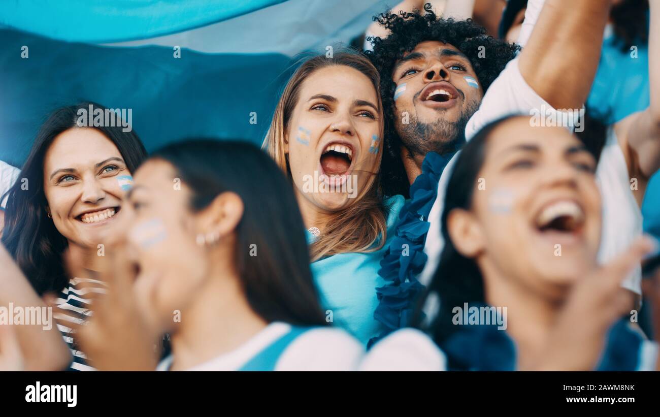 Excited sports fans at live game shouting and cheering for their team. People watching football match chanting to cheer argentinian national team. Stock Photo