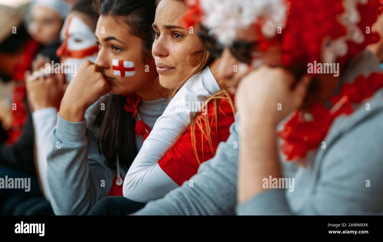 Disappointed fans at sports stadium watching the game in disbelief while their team is losing the match. Upset group of English fans looking sad after Stock Photo