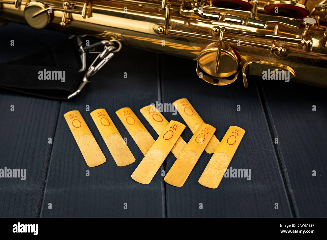 Reeds of the mouthpiece of a sax next to the golden and shiny instrument Stock Photo