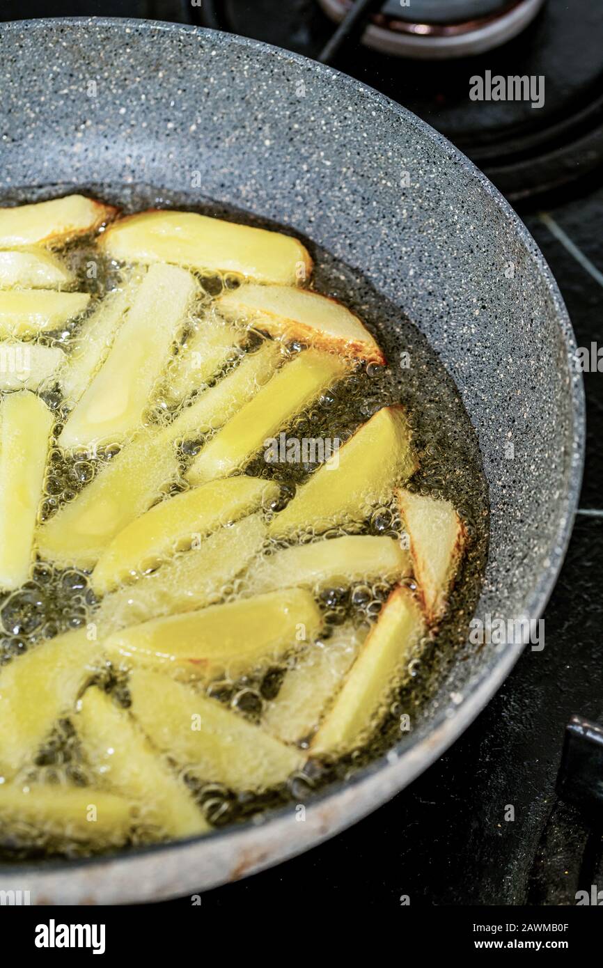 French fries frying in vegetable oil in the pan on the cooker Stock