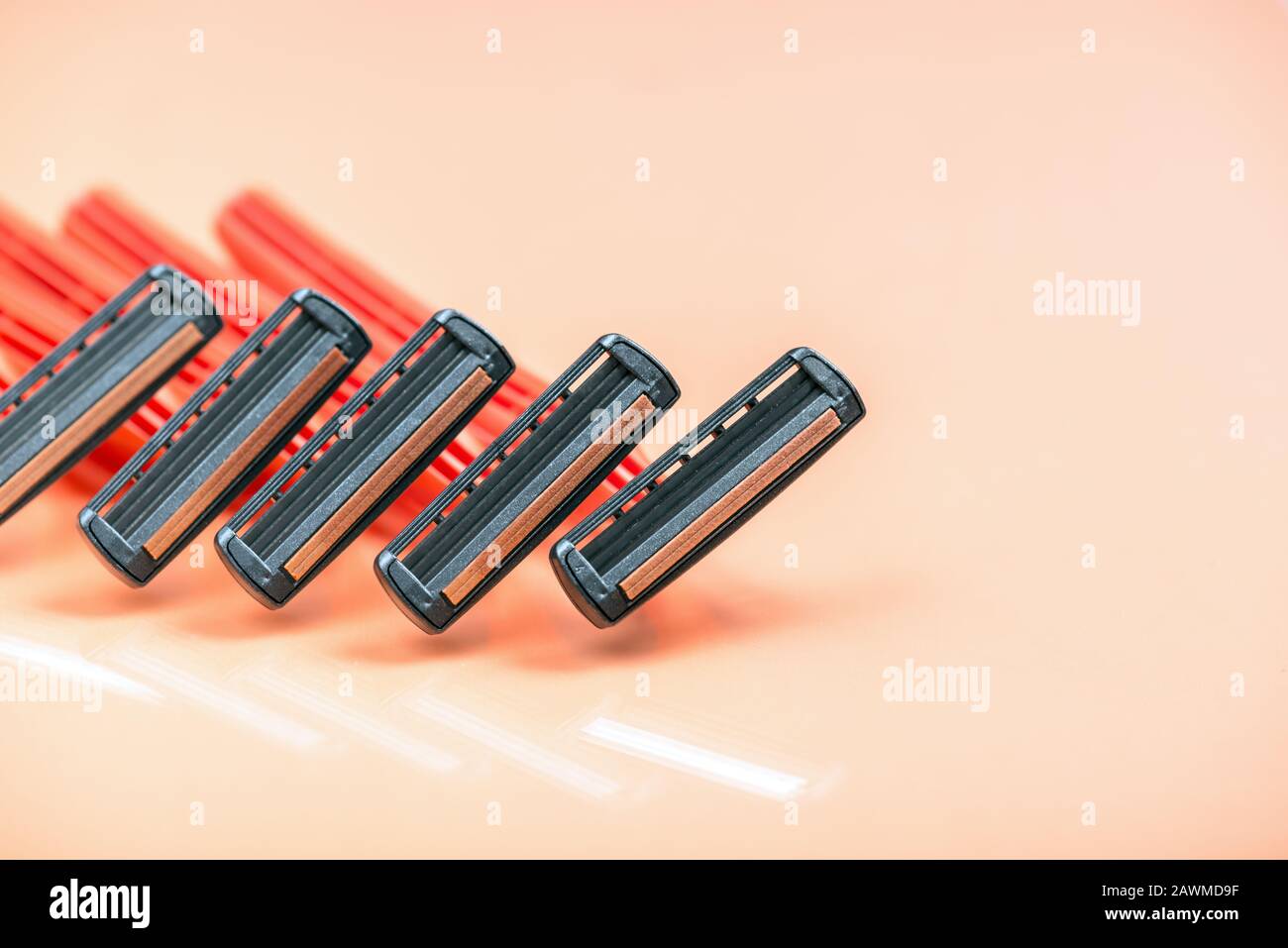 Group of red safety razors on orange color background.  Many Shave blade razors on red surface Stock Photo