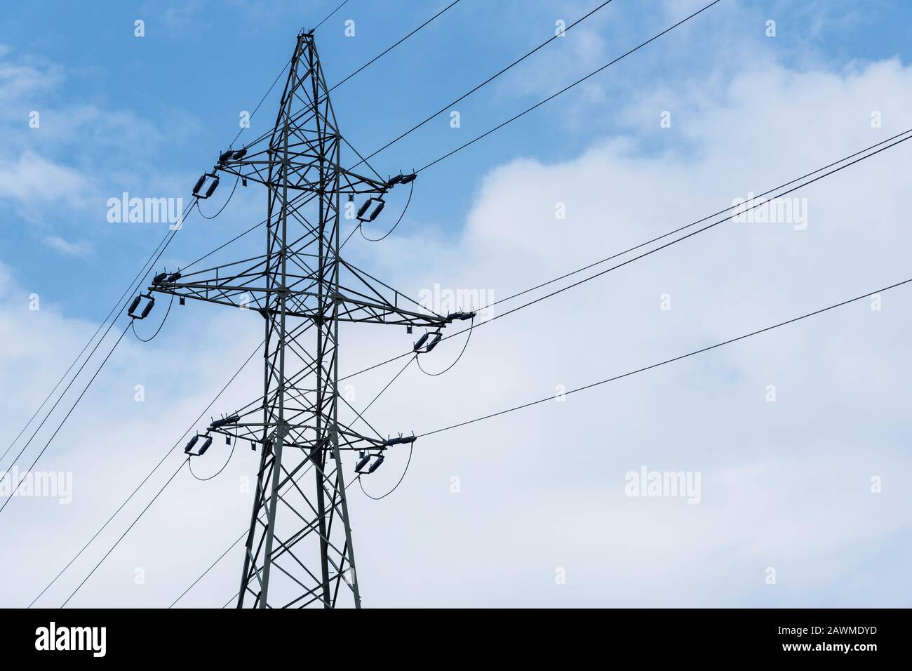 High voltage power line tower on a blue sky with clouds background ...