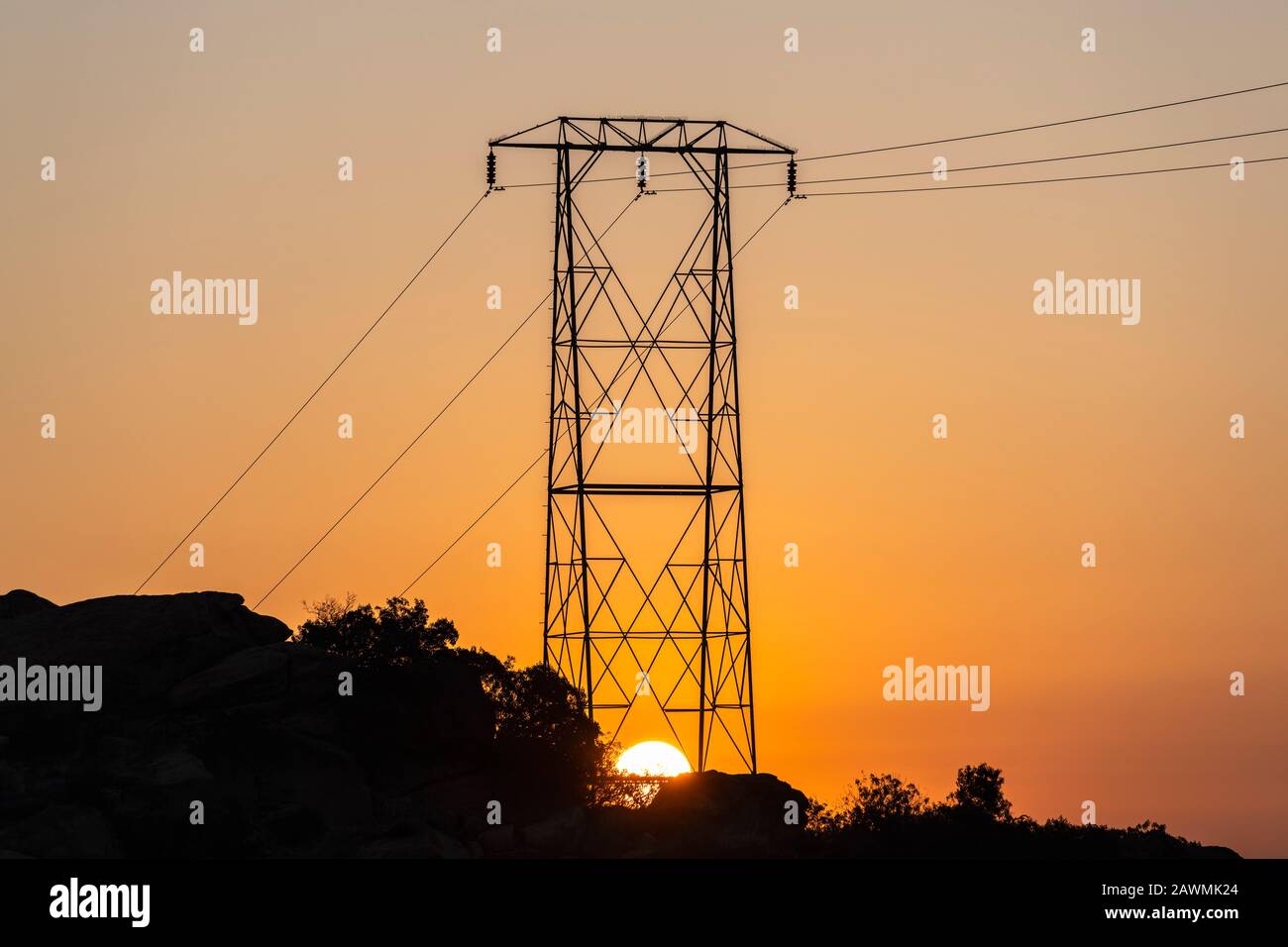 Sun rising below hilltop electric power tower at Santa Susana Pass State Historic Park in Los Angeles California. Stock Photo