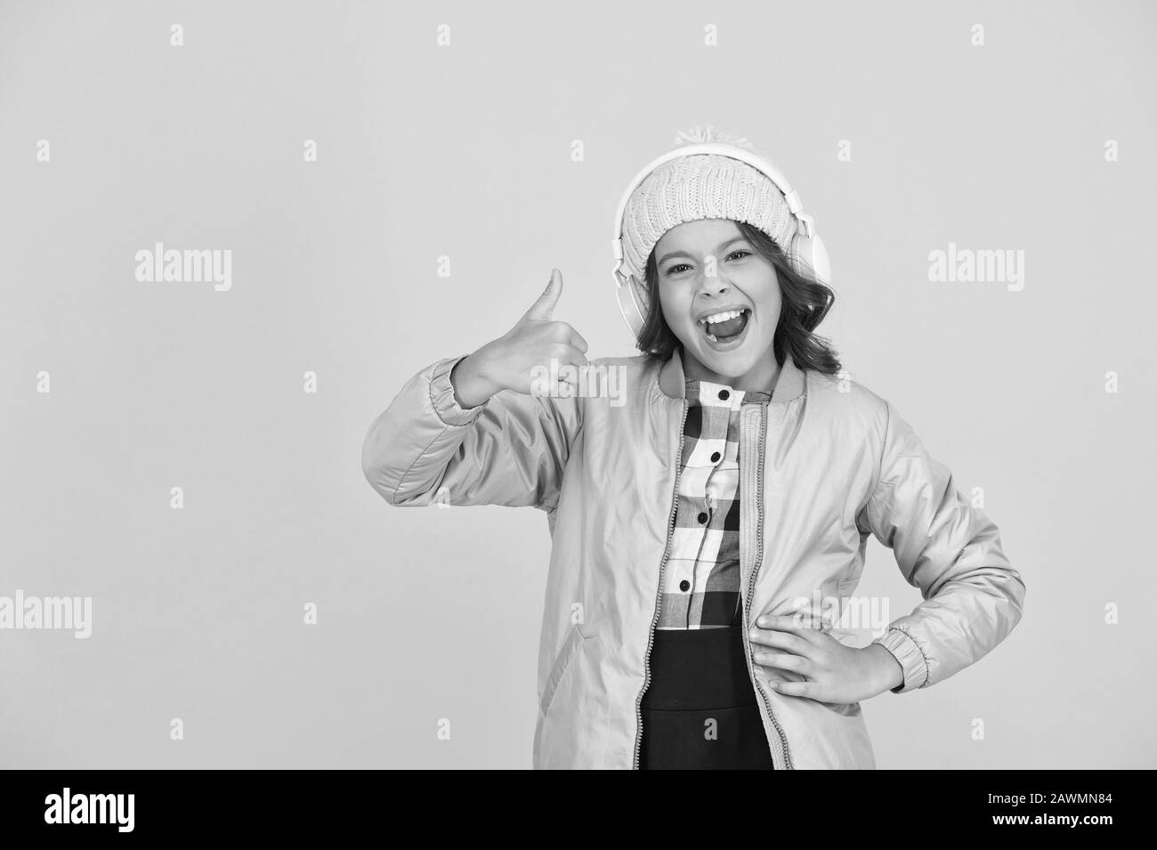 Thumbs up if you like this song. Happy child listen to song yellow background. Little girl enjoy song playing in earphones. Music school and education. Learning through song. Stock Photo