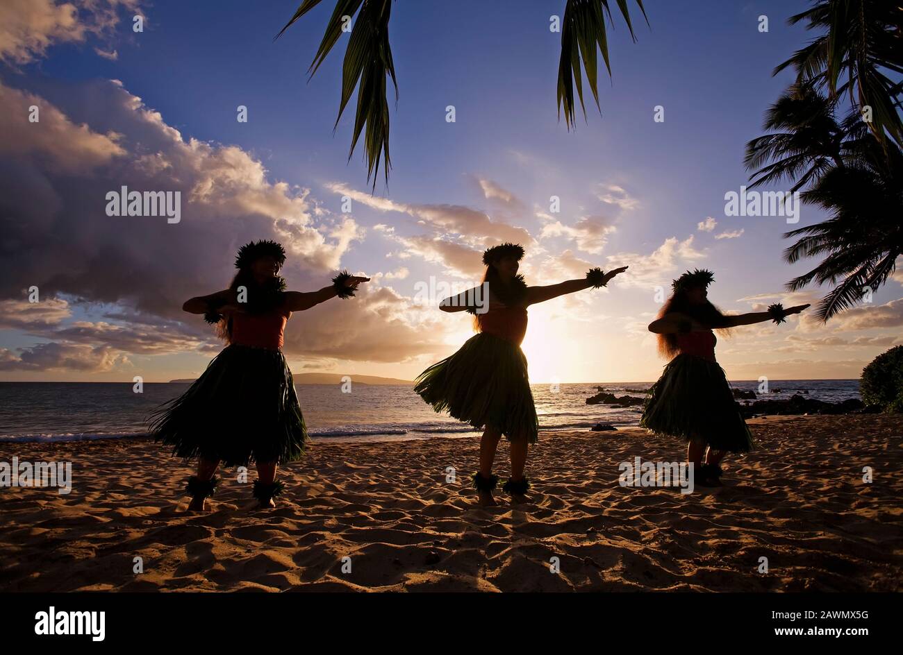 Three hula dancers at sunset at White Rock, Palauea, Maui, Hawaii Stock Photo