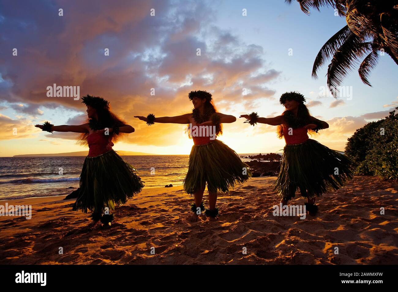 Three hula dancers at sunset at White Rock, Palauea, Maui, Hawaii. Stock Photo