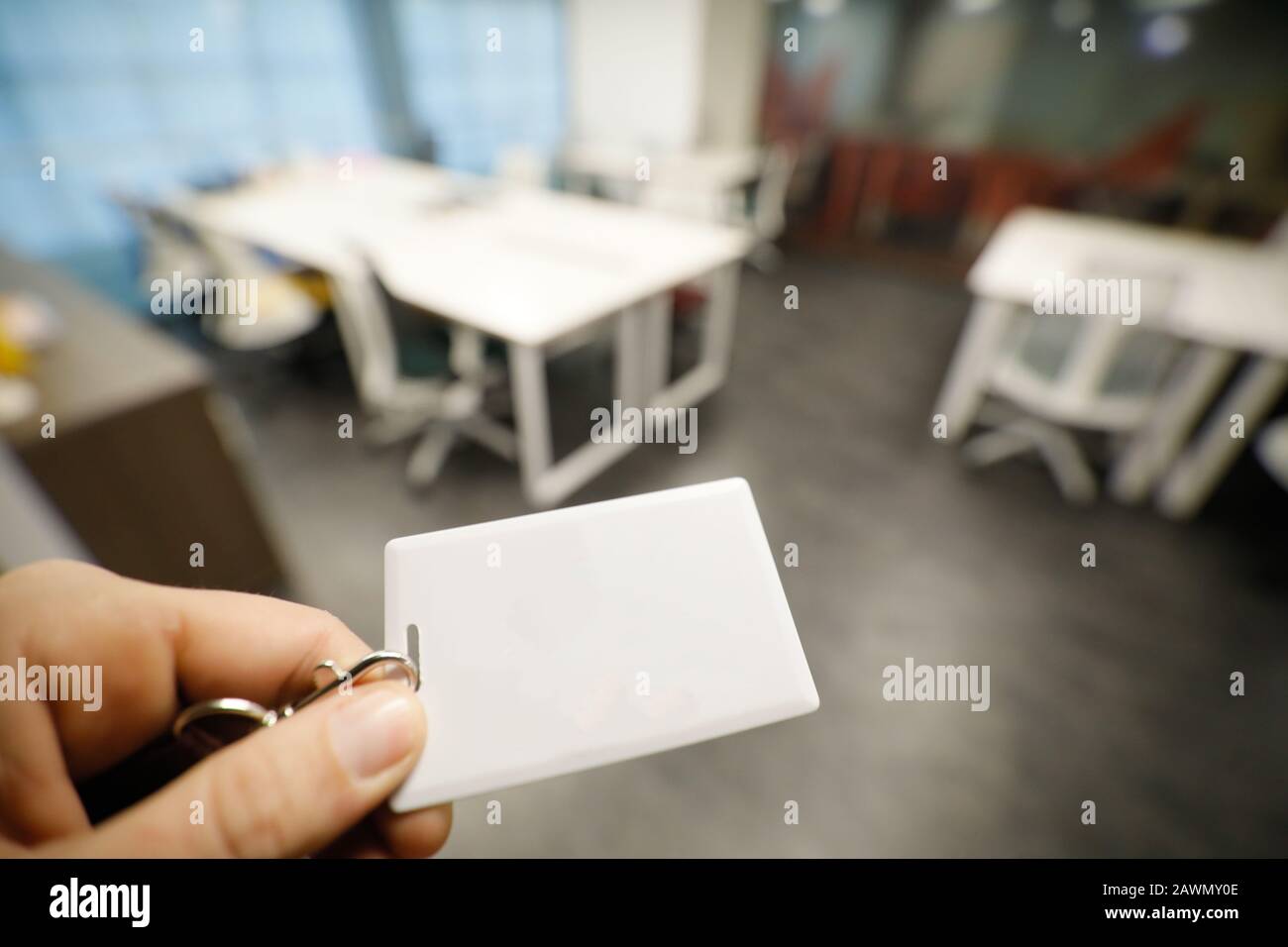 Shallow depth of field (selective focus) image with the hand of a man holding an access card inside an office building. Stock Photo