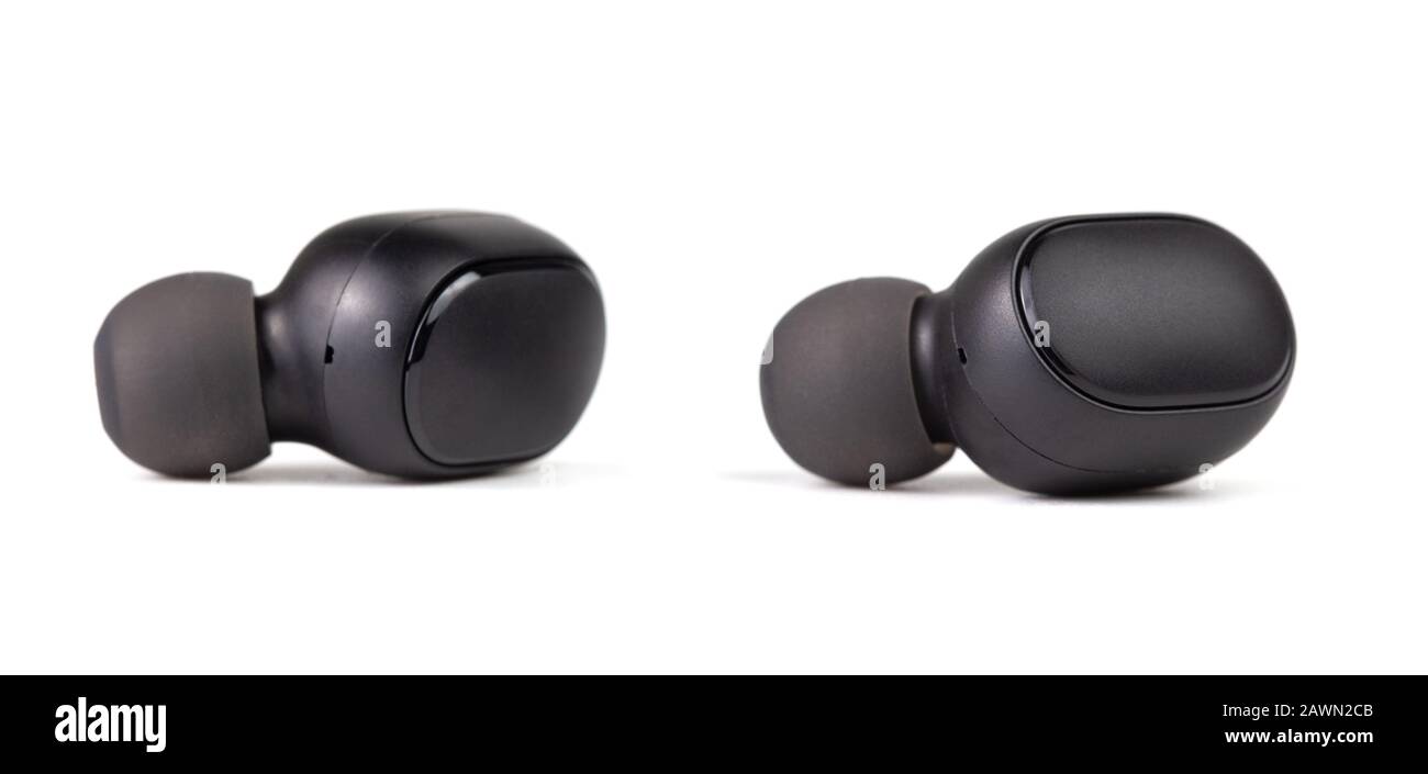 two black wireless bluetooth earbuds isolated on white background - close-up with selective focus. Stock Photo
