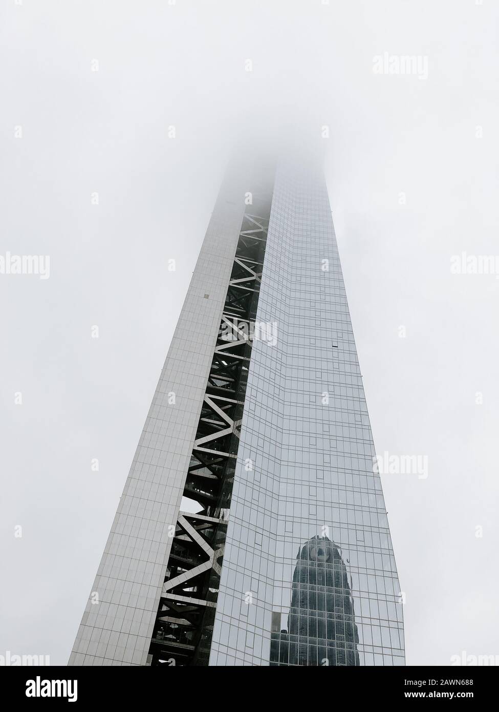 Low angle shot of a tall building with fog covering the top part of it Stock Photo