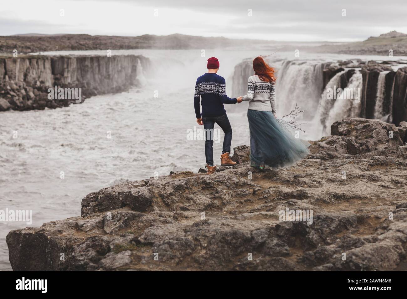 Happy hipster couple in love looking at popular Icelandic Selfoss  waterfall. Traditional wool sweaters, red hair, gray skirt. Dramatic nordic  landscape, cold weather. View from behind Stock Photo - Alamy