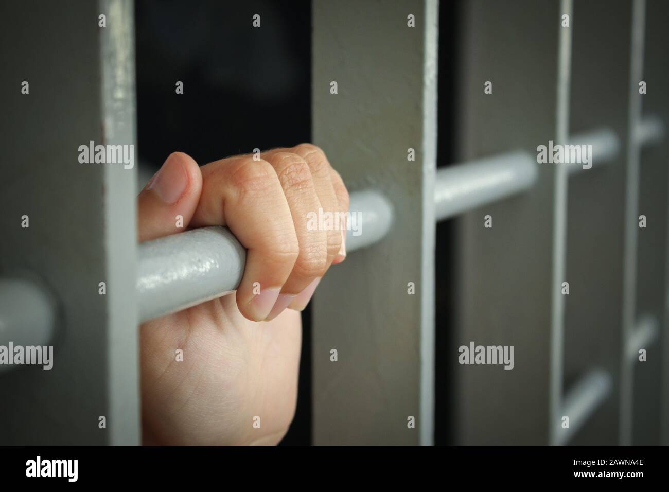Female's hand holding the bars od a cell in a prison - no freedom concept Stock Photo