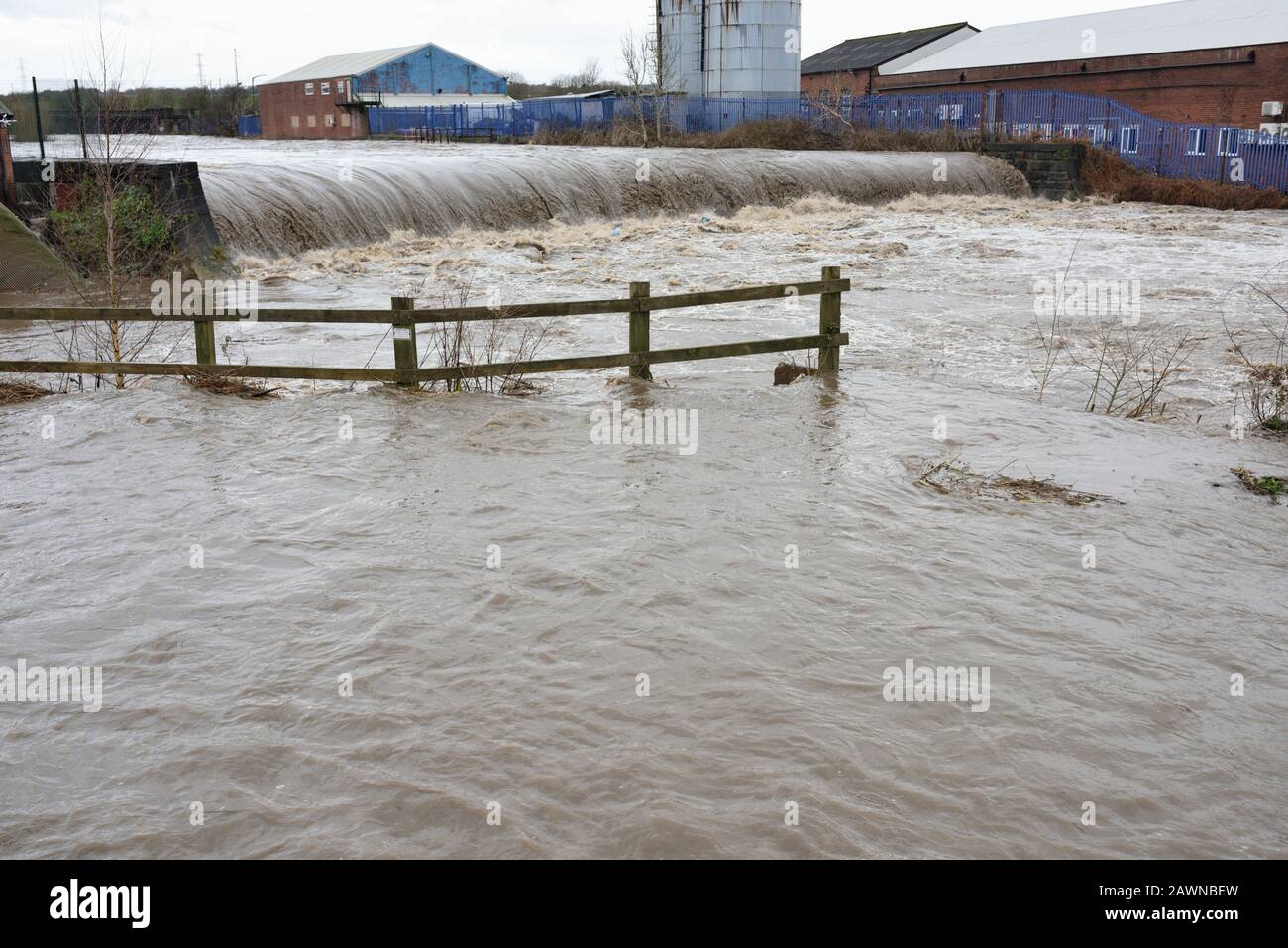Storm ciara, River irwell bursts its banks with industrial buildings in the background in