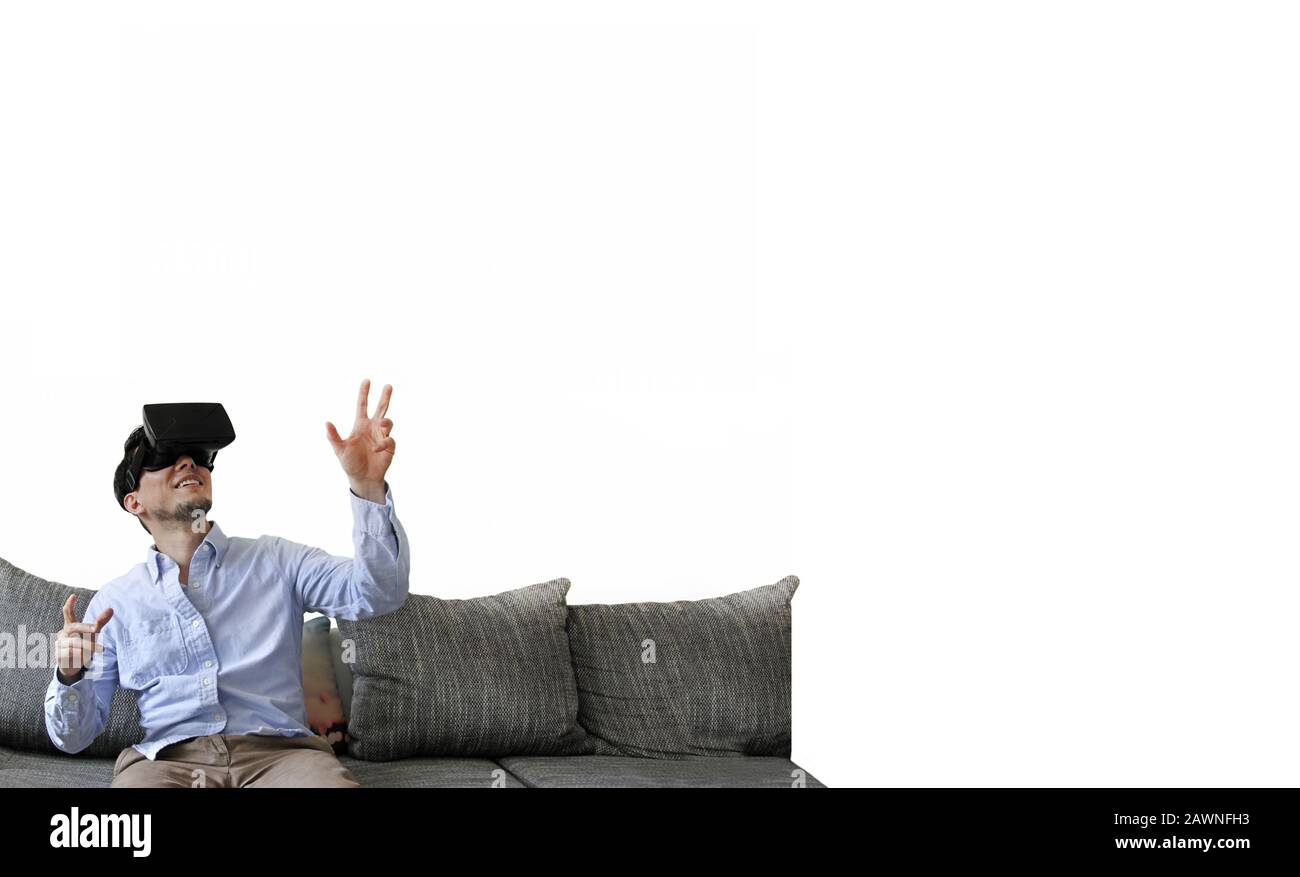 Happily smiling man sitting on the sofa while experiencing virtual reality Stock Photo