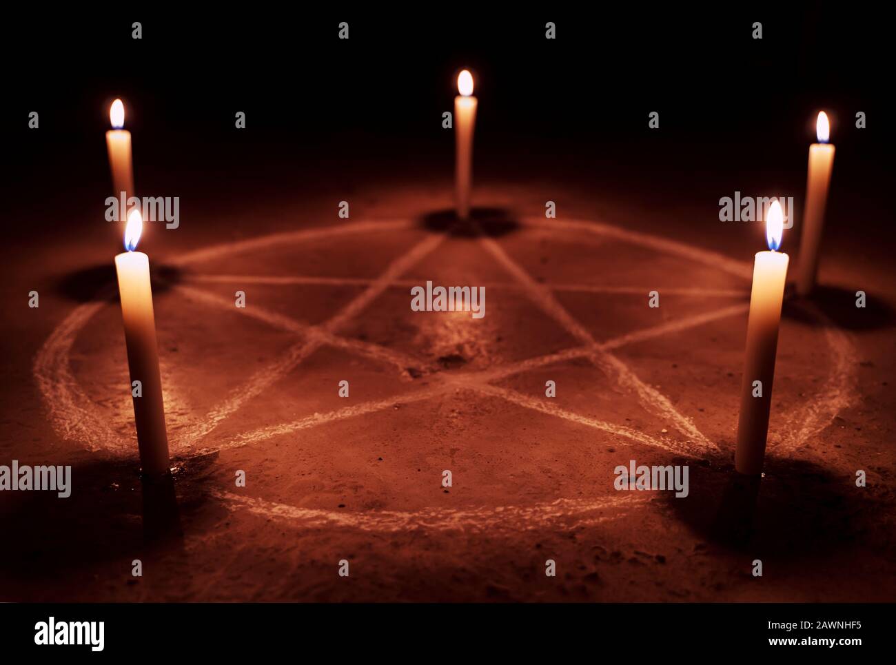 White pentagram symbol on concrete ground. Illuminated with candles. Dark background. Scary, mystical occultism Stock Photo