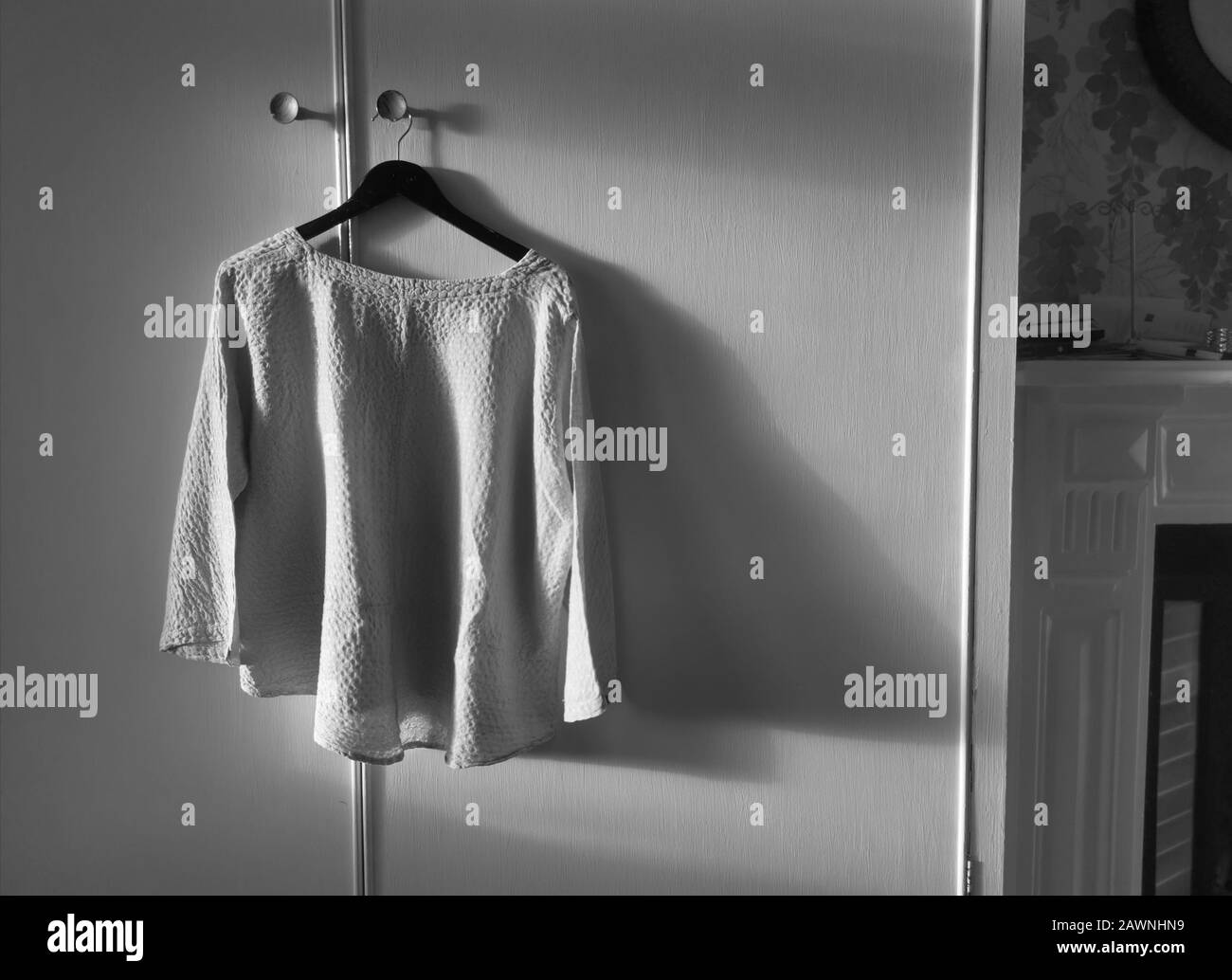 Monochrome image of ladies blouse on hanger with shadows Stock Photo