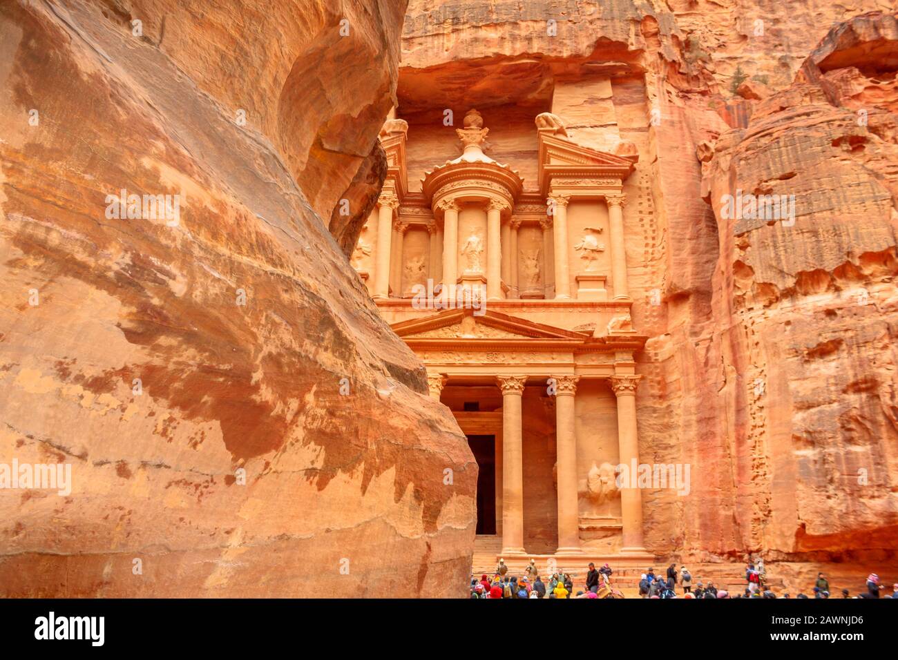Petra, Jordan - Jan 4, 2020: many tourists looking The Treasury seen from the Siq, the main entrance of Petra. Narrow gorge ending with the ruin of Al Stock Photo