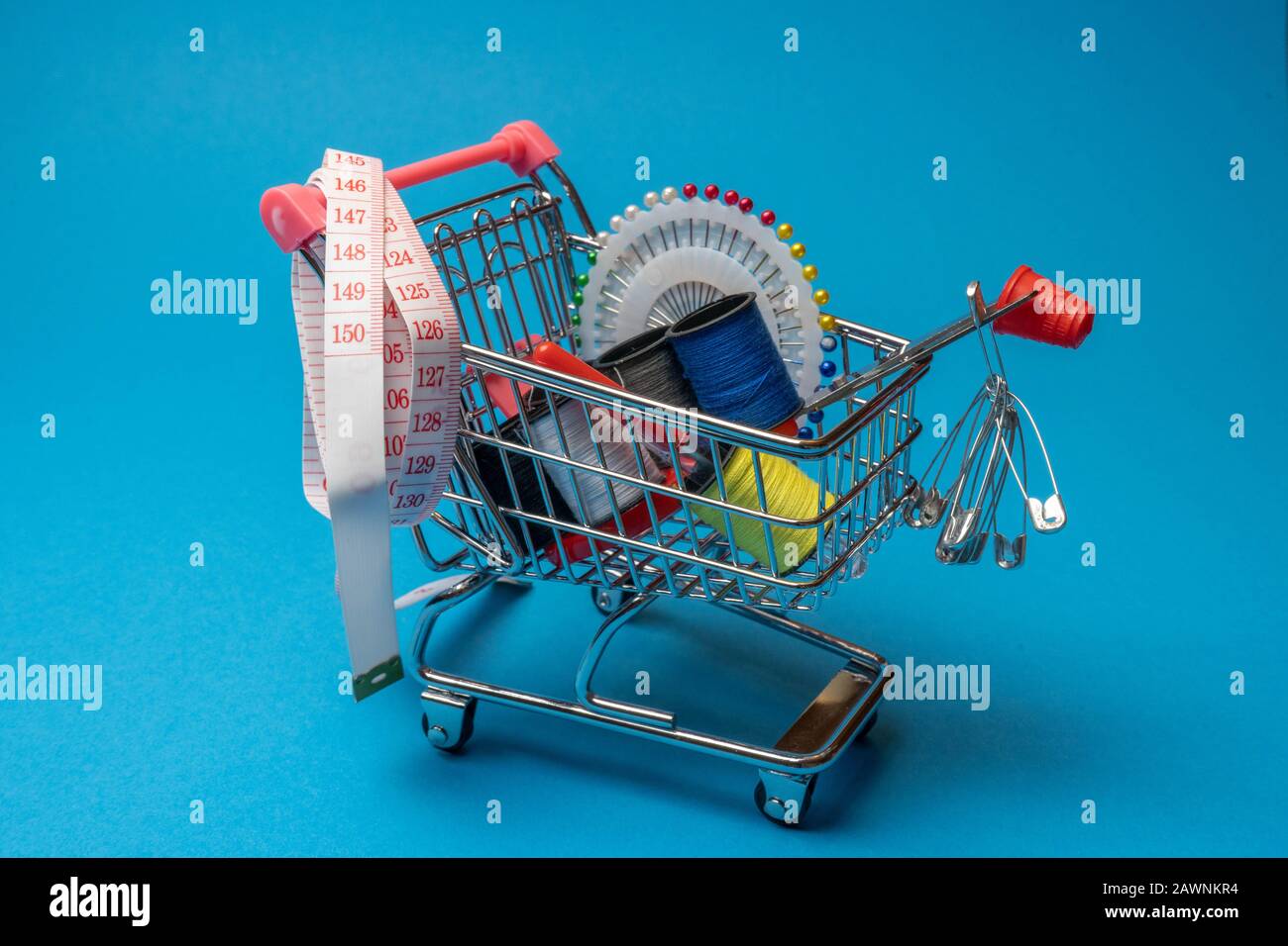 sewing accessories in the grocery basket, needles, threads on a blue background Stock Photo