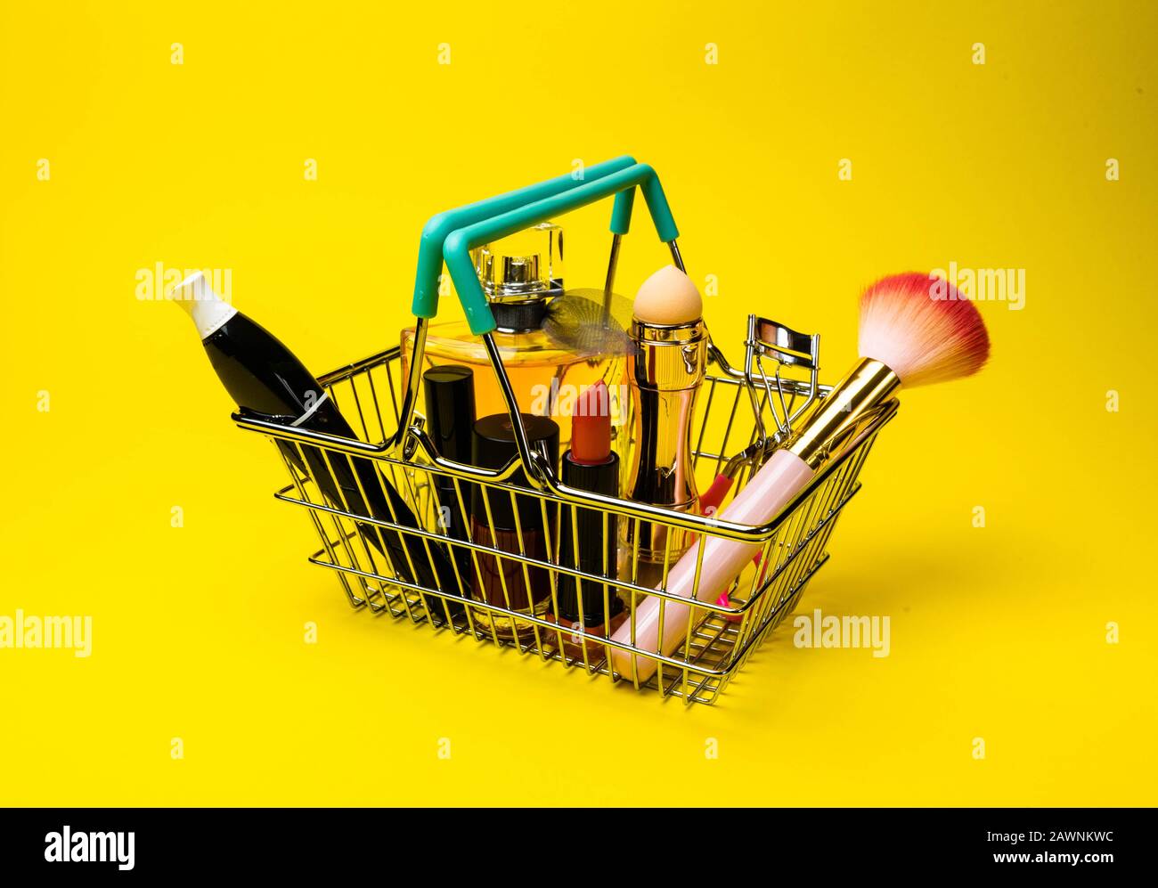 Makeup products fondant, mascara, perfume, brush, with cosmetic bag shopping cart on color background yellow Stock Photo