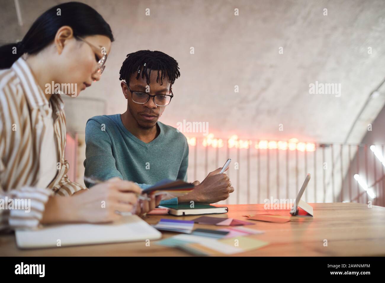 Portrait of two contemporary students working on project together while sitting at table in library, copy space Stock Photo