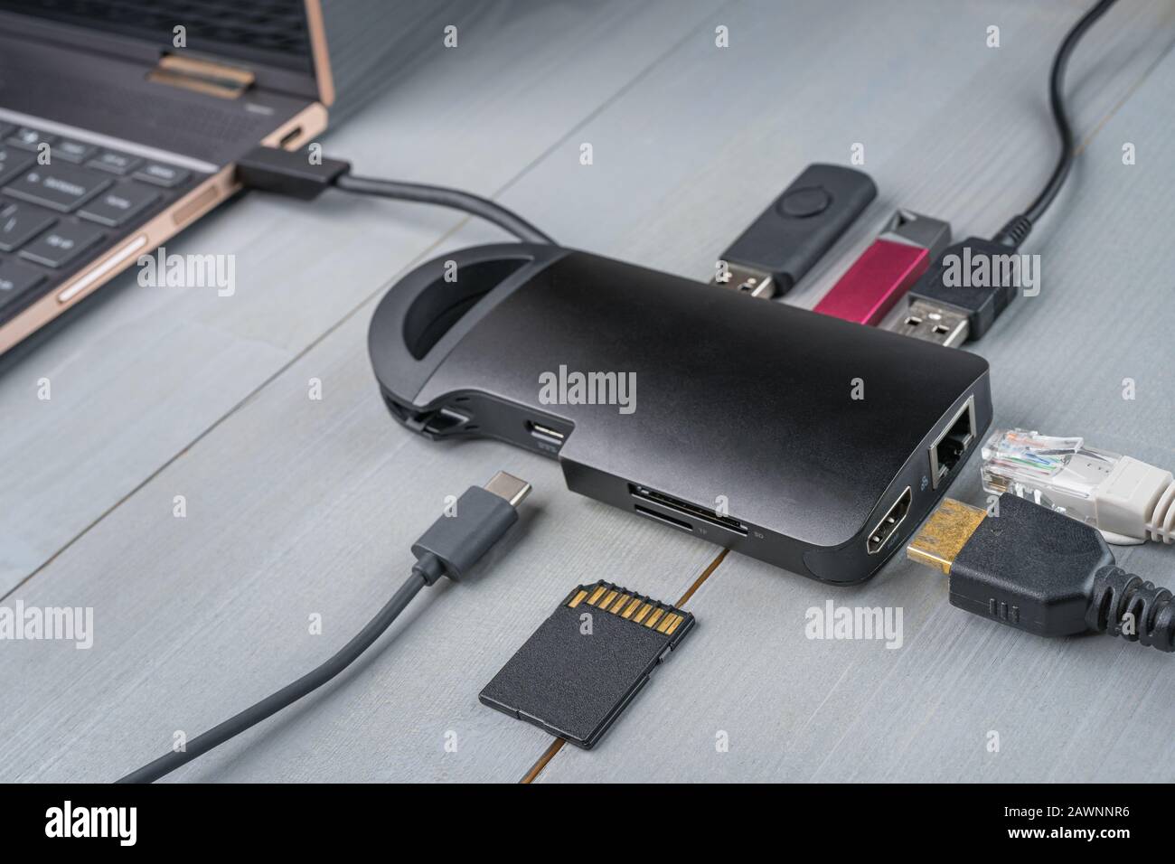 USB Type C adapter or hub connected to the laptop with various accessories - pendrives, hdmi, ethernet, memory card, cables. Stock Photo